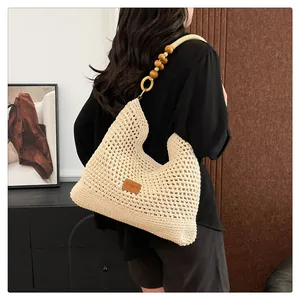 Detail van gebroken witte geweven shopper met houten kralenriem en leren logo