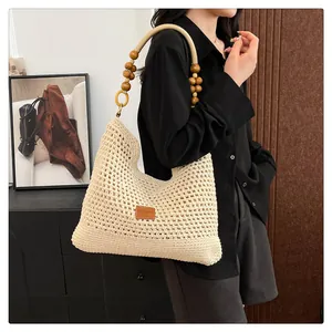 Détail du sac cabas crème tissé main avec perles en bois naturel et écusson en cuir