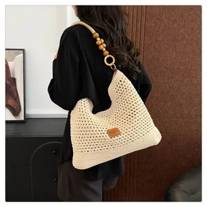 Détail du sac cabas crème tissé à la main avec bandoulière en perles de bois et logo cuir