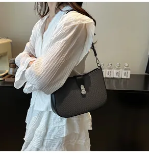 Close-up of black woven texture shoulder bag with silver metal buckle and leather trim