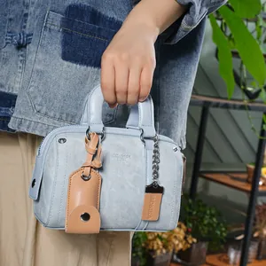 Detail of light blue Boston bag with leather charms and silver hardware on denim outfit