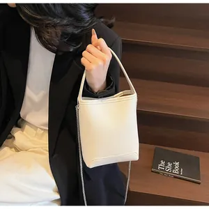 Detail van crème witte bucket bag met lychee patroon en zilveren ketting op de trap