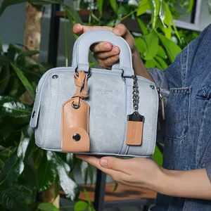 Close-up of light blue mini Boston bag with denim texture and silver chain tag