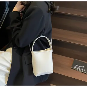 Detail van witte crossbodytas in leder met litchipatroon en metalen ketting