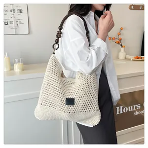Détail du sac cabas crème tissé main avec perles en bois et écusson logo en cuir