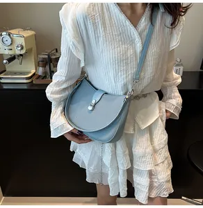 Detail of light blue textured saddle bag with silver buckle and leather shoulder strap