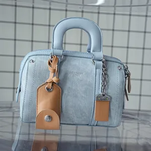 Detail of light blue denim texture mini Boston bag with embossed logo and metal charms
