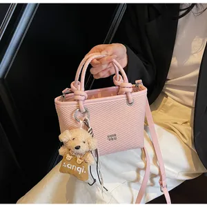Pink textured leather bucket bag with cute plush bear charm and silver metal logo