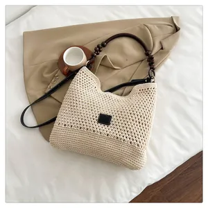 Detail van de handgeweven draagtas met leren riemen en decoratieve houten kralen