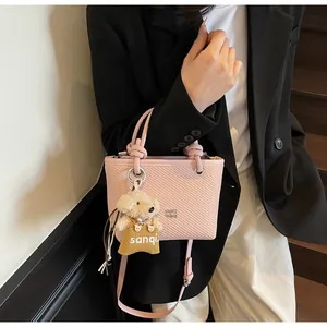 Detail of pink crossbody bucket bag with woven texture and a cute plush bear charm