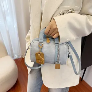 Light blue Boston pillow bag with brown leather handles and a silver chain detail