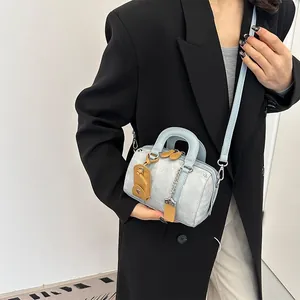 Light blue Boston mini handbag with crossbody strap and brown accents shown on model
