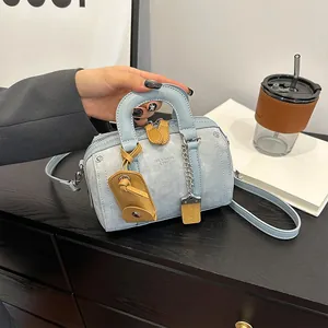 Blue denim texture mini Boston bag with metal chain and shoulder strap on a cafe table