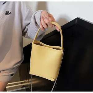 Detail van gele mini emmer tas van litchi leer met metalen ketting en handvat