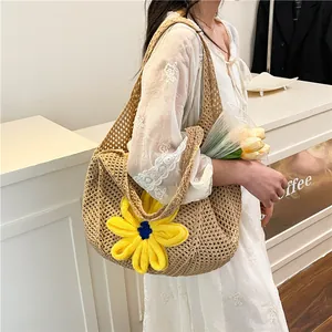 Beige hollow woven straw tote bag with a large yellow knit flower for beach and commute