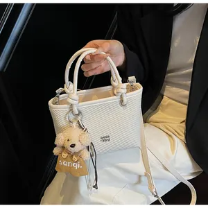 White woven tote bag detail featuring round handles and a cute plush puppy pendant