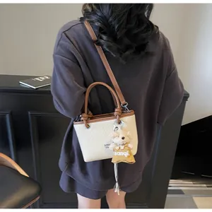 Model view of mini woven tote bag with brown leather handles and cute bear charm