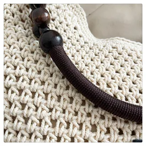 Gros plan détaillé du sac cabas tissé crème avec des accents de perles en bois marron