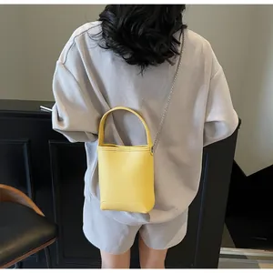 Achteraanzicht van een model met een felgele mini crossbody emmertas van generfd leer