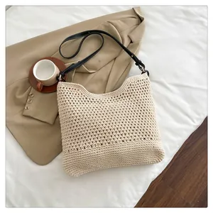 Detail van handgeweven crème draagtas met zwarte leren riem op minimalistische basis