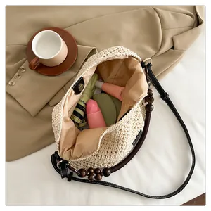 Vue intérieure du grand sac cabas tressé beige avec anse en perles de bois et accessoires