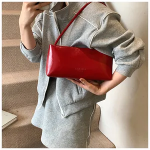 Close-up of vibrant red patent leather underarm bag with embossed fashion logo detail
