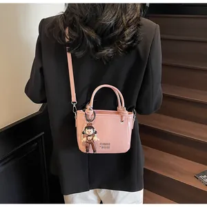 Close-up of pink mini bucket bag with glossy finish and cute cartoon character pendant