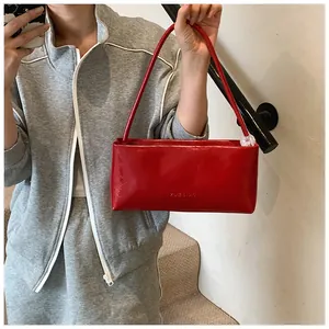 Detailed view of a bright red rectangular handbag with brand embossing on the side