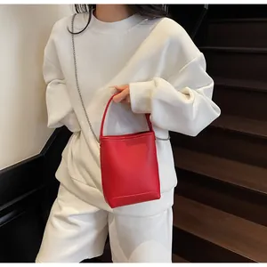 Detail van rode bucket bag met lychee-textuur en zilveren metalen kettingriem
