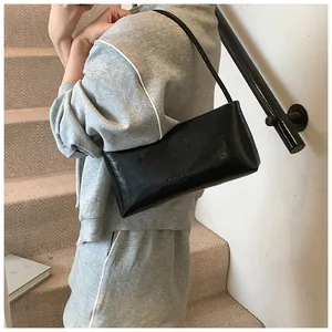 Detail of minimalist black patent leather shoulder bag with embossed brand logo
