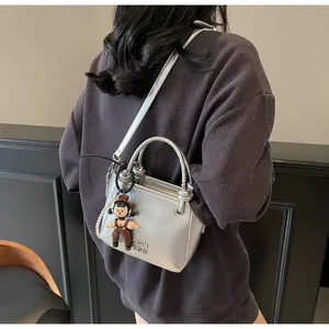 Detail of silver metallic bucket bag with pearl chain and fashion charm on shoulder