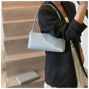 Detail of light blue faux leather baguette bag with beaded strap on wooden stairs