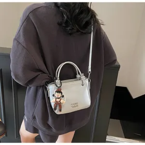 Silver mini bucket bag with doll charm shown from behind on model for size perspective