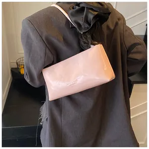 Detail of pink faux leather handbag with embossed fashion logo on model's shoulder