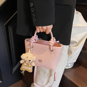 Pink woven bucket handbag with knot handle and plush dog charm for women