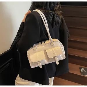 Detail of cream patent leather bowling bag showing front buckle pockets and shoulder strap