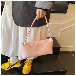 Chic pink underarm bag with brand embossing and decorative bead on a slim shoulder strap