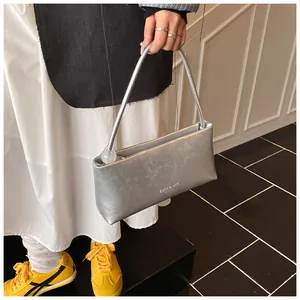 Detail of silver metallic pleated handbag featuring a clear spherical charm and branding