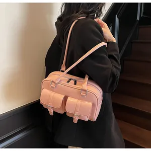Detail view of pink glossy shoulder bag featuring double front flap pockets and metallic buckles
