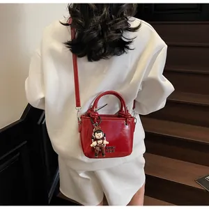 Close-up of vibrant red bucket bag with glossy finish and cute cartoon charm