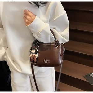 Detail of vintage dark brown bucket bag featuring metal embossing and cute doll charm