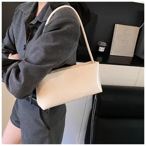 Detail of off-white leather underarm bag with ZSKERBAG logo held by a model
