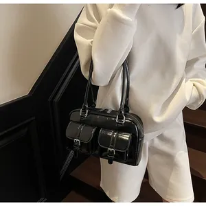 Detail of glossy black bowling bag with decorative front buckle pockets and shoulder strap