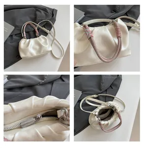 Detail of cream pleated cloud bag featuring colorful braided handle and zipper closure
