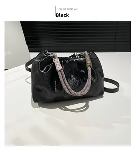 Detail of black pleated cloud bag with rainbow braided handle and adjustable strap