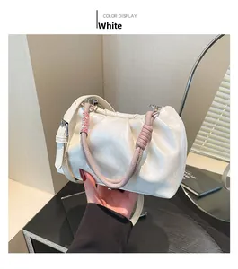 Detail of white pleated cloud bag with pink woven handle and adjustable strap in hand