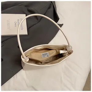 Close-up of cream shoulder bag with polished finish and a clear sphere charm detail