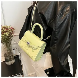 Detail of lime green crossbody bag with bear embossing and silver rotating metal clasp