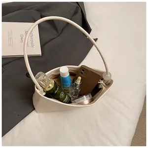 Top view of cream white underarm bag showing interior space with phone and perfume