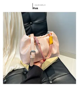 Detail of pink ruched cloud bag featuring vibrant yellow braided rope handles and leather strap